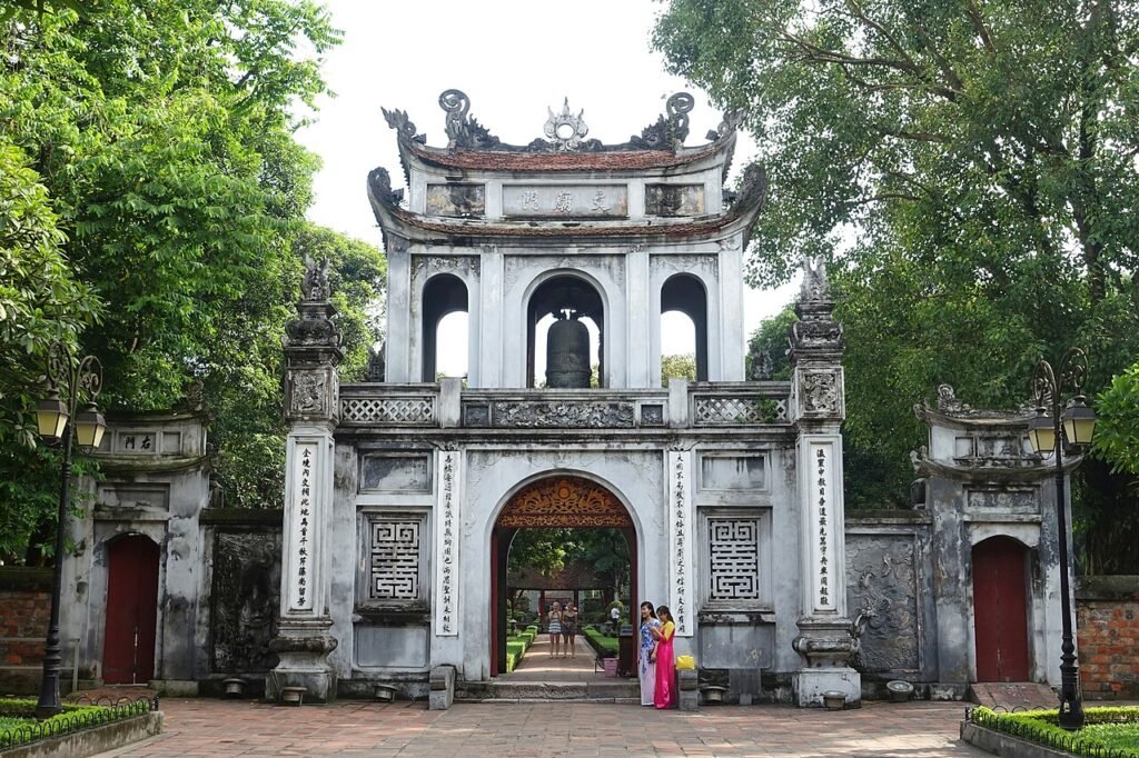 The ornate stone main gate of the Temple of Literature in Hanoi, framed by trees