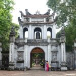 The ornate stone main gate of the Temple of Literature in Hanoi, framed by trees