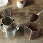 Ground coffee being scooped into a Vietnamese phin filter