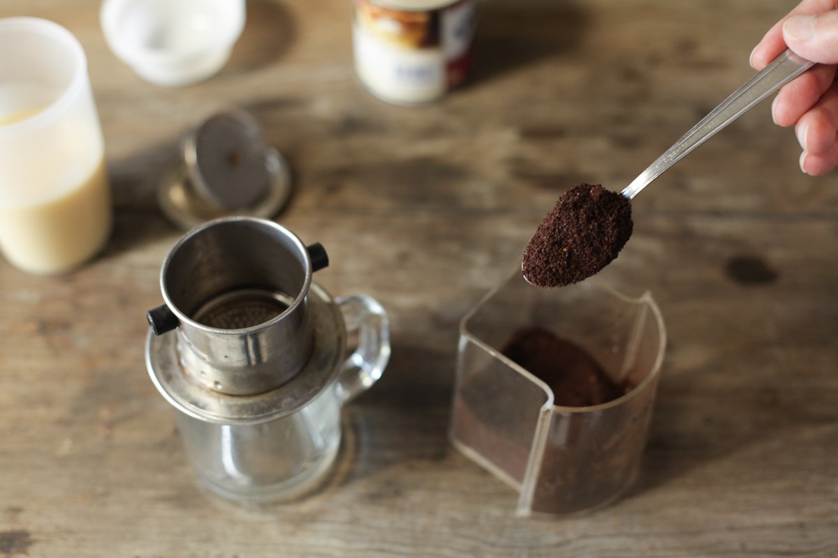 Ground coffee being scooped into a Vietnamese phin filter