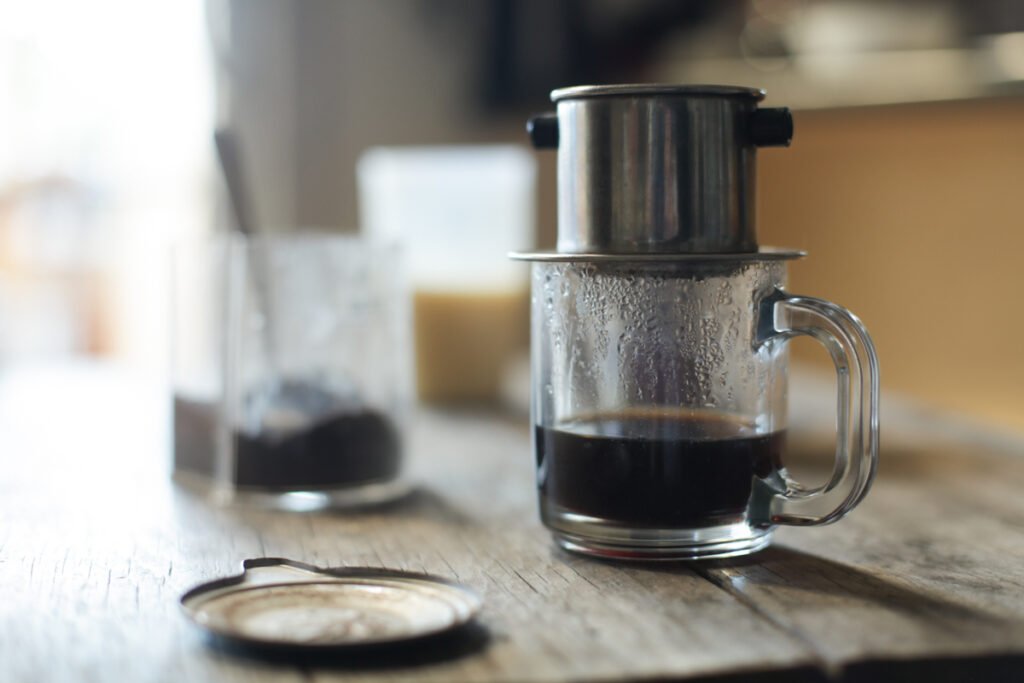 Vietnamese coffee dripping through a metal phin filter into a cup