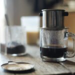 Vietnamese coffee dripping through a metal phin filter into a cup